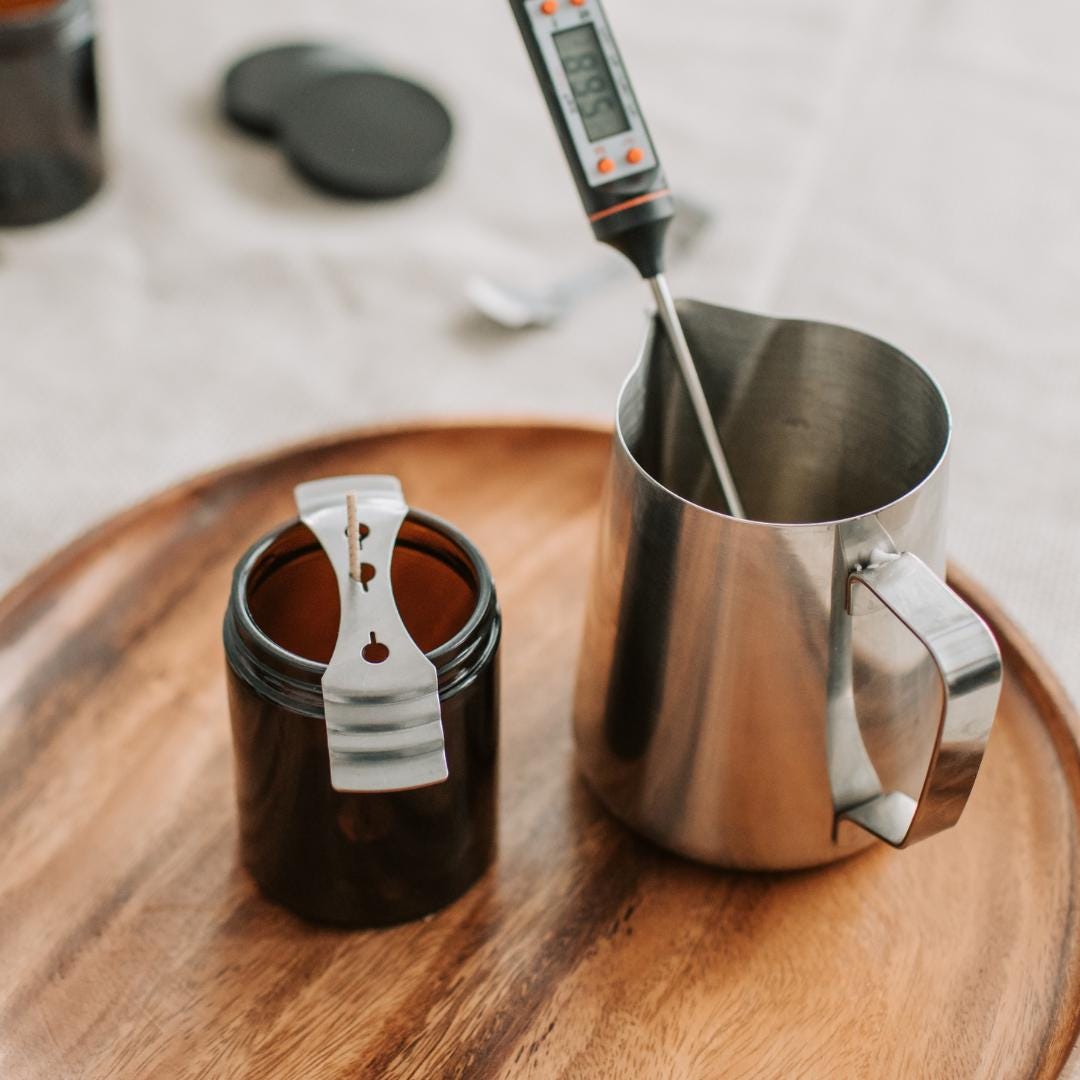 a wooden tray topped with a metal cup and a measuring cup