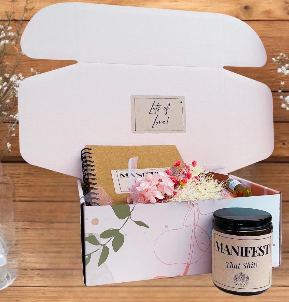 a box of flowers, a notepad, manifesting gift box with candle and notebox